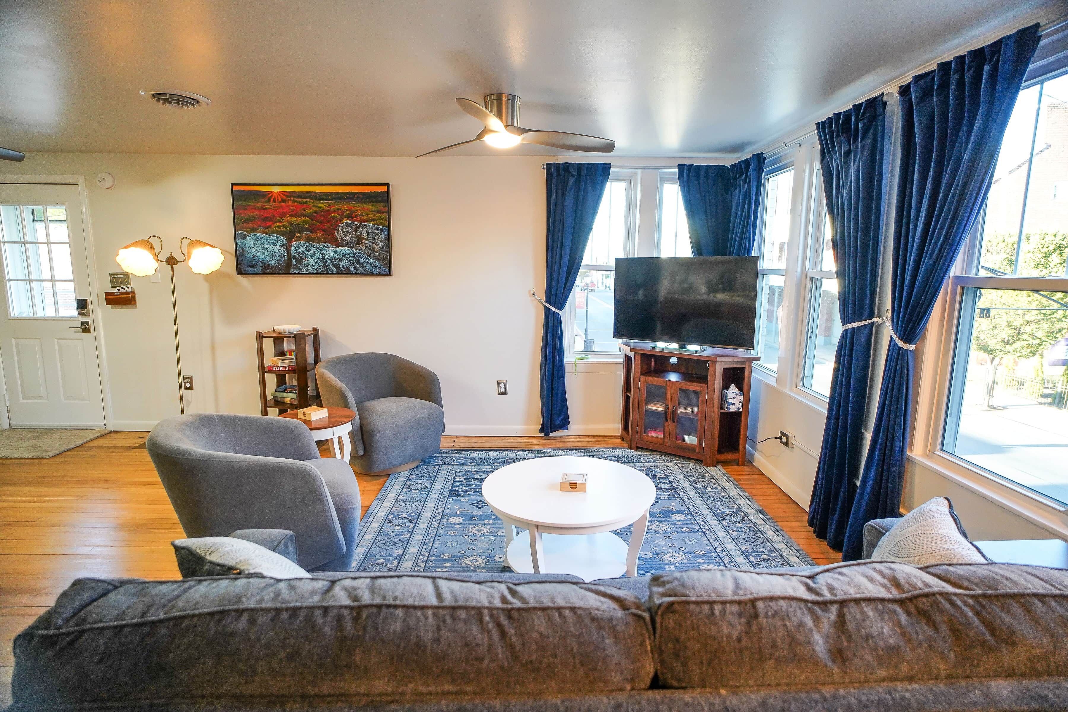 A living room with a sofa, armchairs, a coffee table, a television, and a painting on the wall.