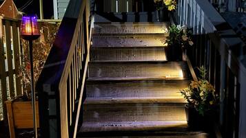 A wooden staircase with a railing, leading to a door with a geometric glass design.