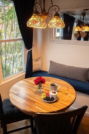 A cozy room with a round wooden table, a blue sofa, and a window with curtains. - Downing Suite Moorefield W.V. (Moorefield)