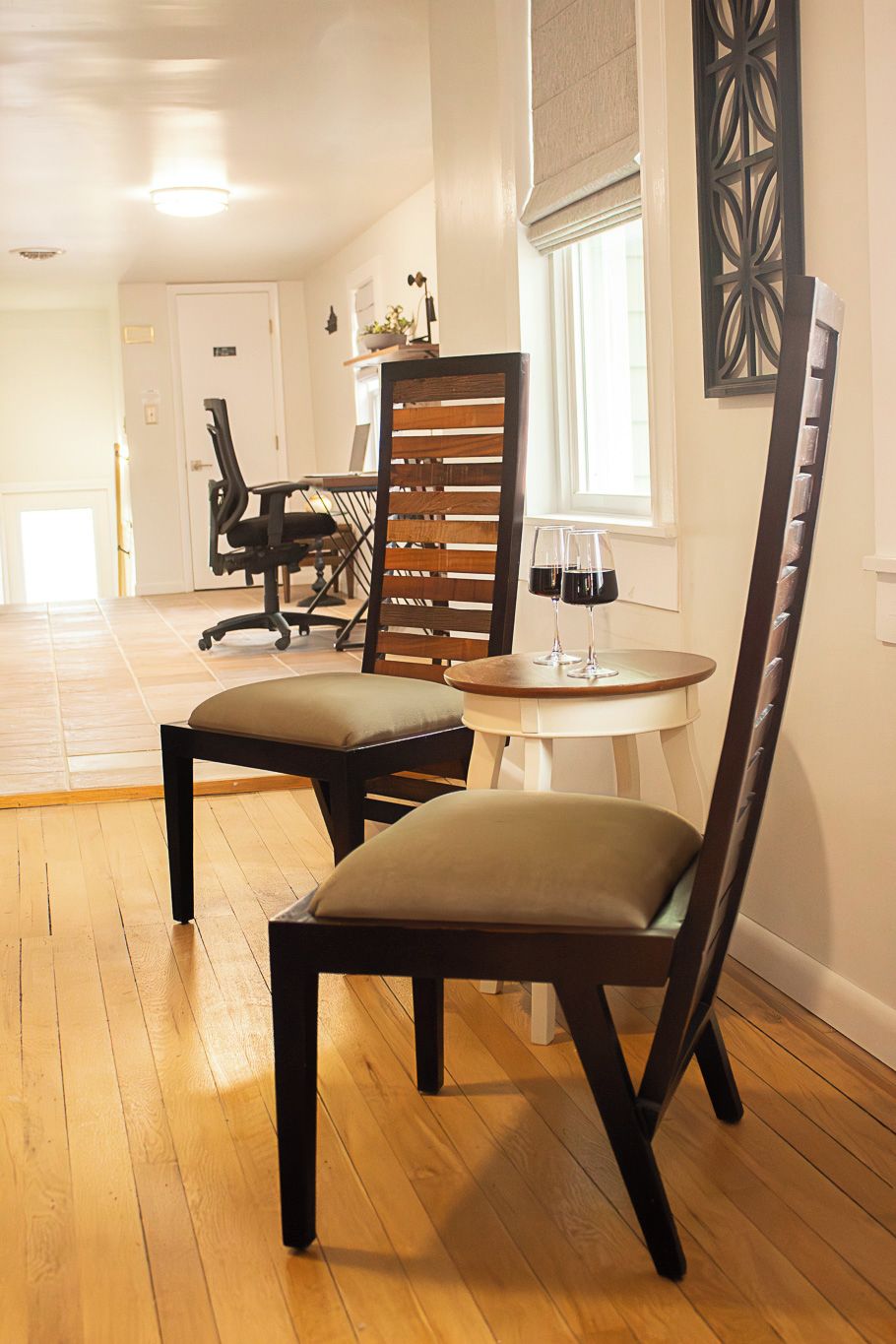 A dining area with two chairs, a table, and a window with blinds.