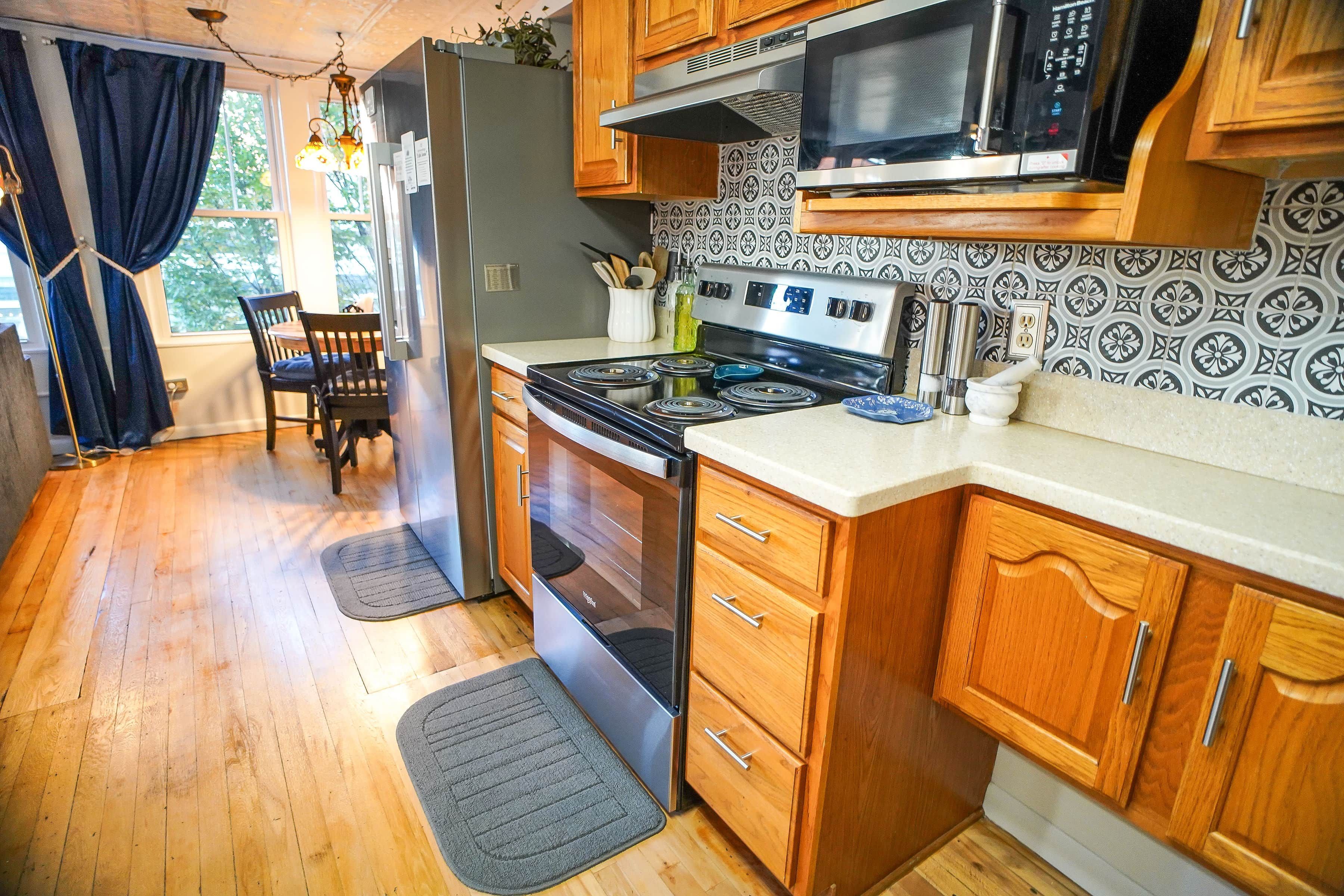 A compact kitchen with wooden cabinets, a stove, a microwave, and a refrigerator.