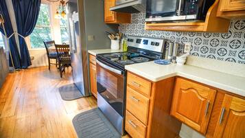 A compact kitchen with wooden cabinets, a stove, a microwave, and a refrigerator.