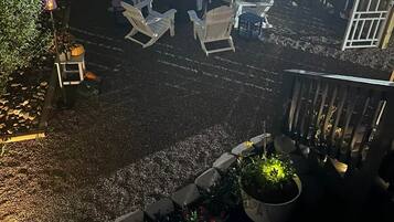 An outdoor seating area with chairs and tables, surrounded by a wooden fence and decorative lighting.