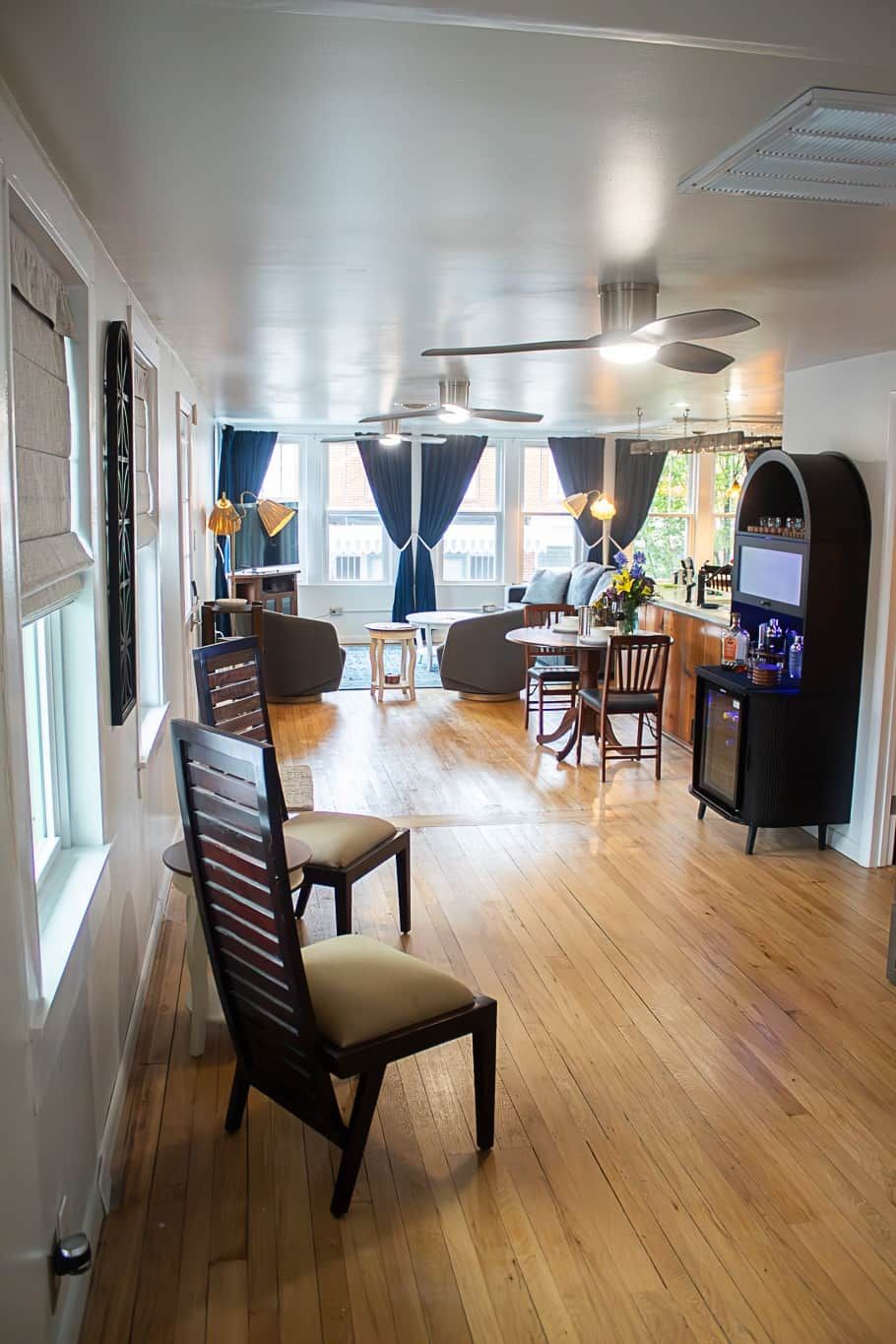 A spacious room with a wooden floor, a bar area, and seating arrangements.