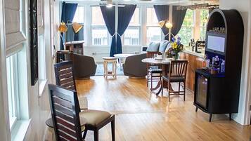 A spacious room with a wooden floor, a bar area, and seating arrangements.
