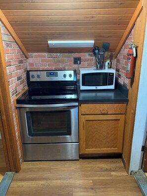 A compact kitchen with a stainless steel stove, a microwave, and wooden cabinets.