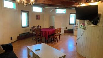 A dining area with a table and chairs, a white cabinet, and a television mounted on the wall.