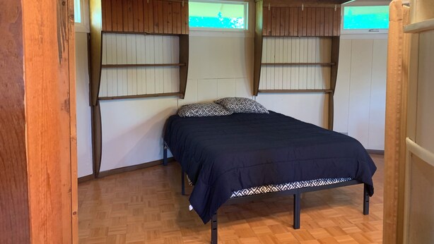 Ein Schlafzimmer mit einem Bett, Holzwänden und einem Fenster.