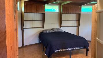 A bedroom with a bed, wooden walls, and a window.