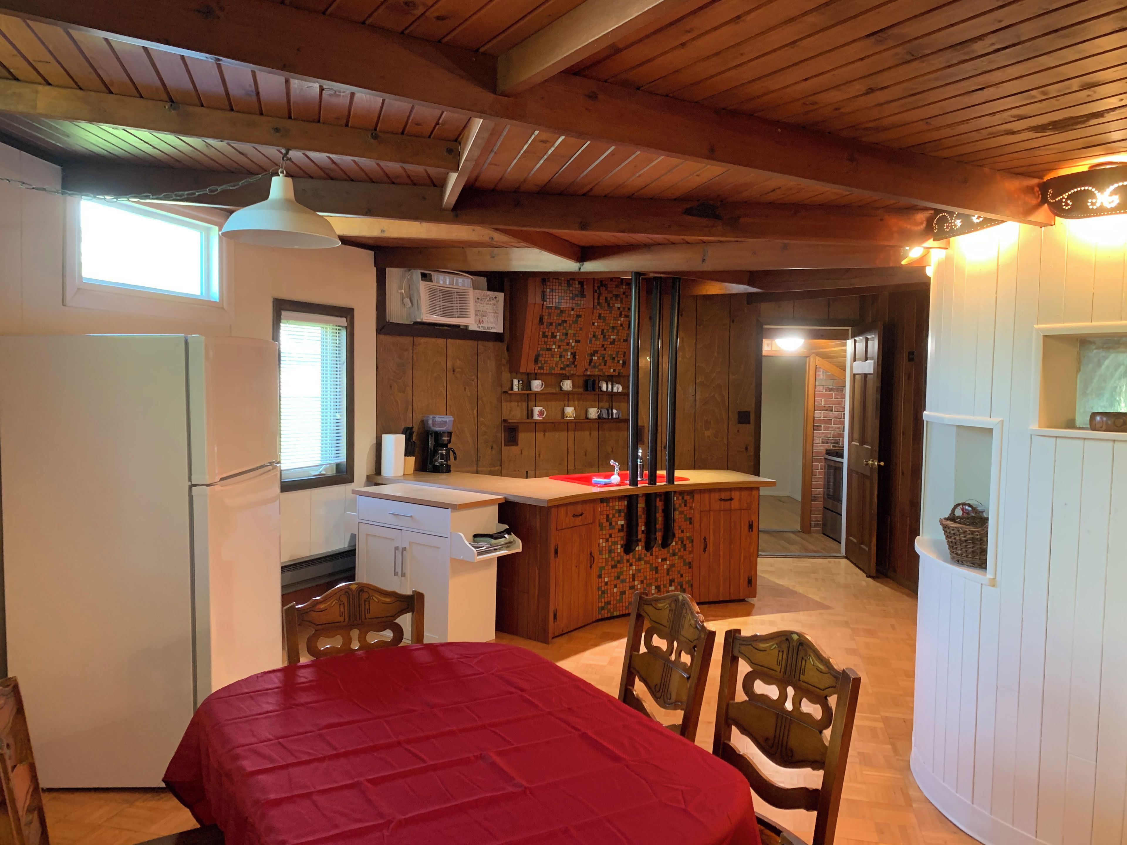 A compact kitchen with a refrigerator, a coffee maker, and a microwave. There is a dining area with a table and chairs.