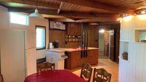 Eine kleine Küche mit Kühlschrank, Kaffeemaschine und Mikrowelle. Ein Essbereich mit Tisch und Stühlen ist ebenfalls vorhanden.