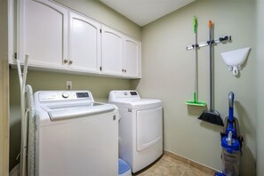 A laundry room with a washing machine, dryer, cabinets, and cleaning tools. - Lake Retreat / 2 Private Sides / King Beds / Kayak (Seguin)