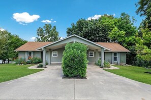 A two-story house with a covered front porch, a small front yard, and a large tree in the center. - Lake Retreat / 2 Private Sides / King Beds / Kayak (Seguin)