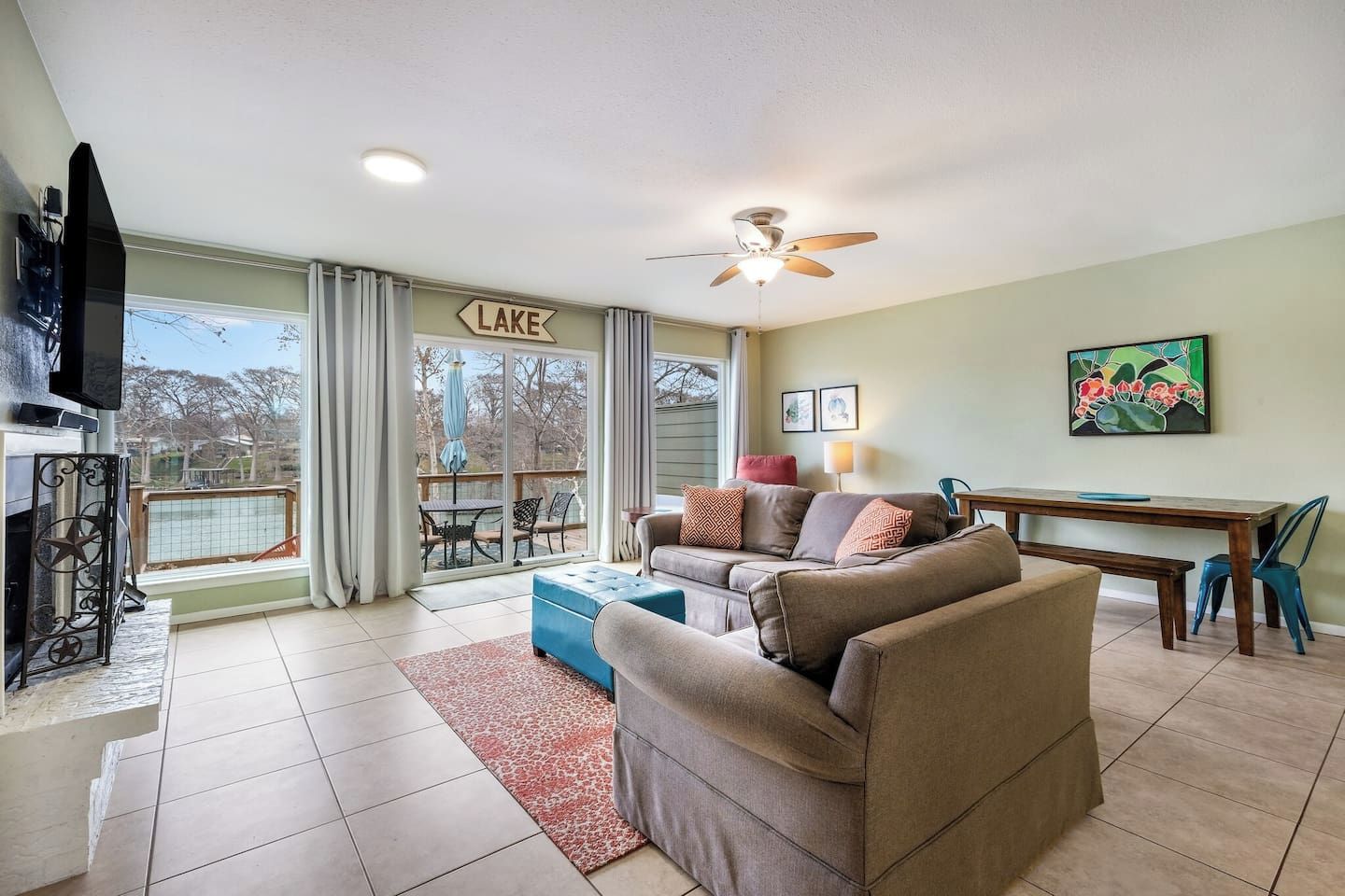 A living room with a sofa, a TV, a ceiling fan, and a dining area with a table and chairs.