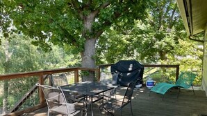 Una terraza al aire libre con mesa y sillas, una parrilla y un área techada.
