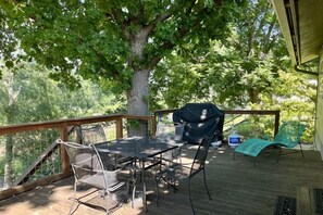 Een terras buiten met een tafel, stoelen, een barbecue en een overdekt gedeelte.
