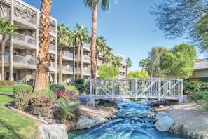 A hotel with multiple balconies, a bridge over a stream, and lush greenery. - WM BLOCK Indio Studio (Indio)