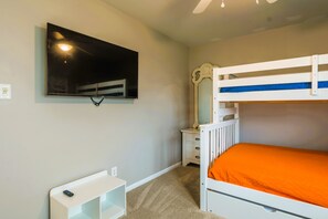 Ein Schlafzimmer mit Etagenbetten, einem Fernseher, einem Nachttisch und einer Kommode.