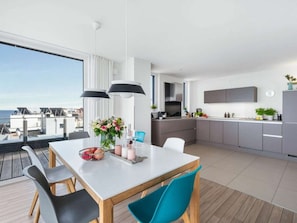 A modern kitchen with a dining area, large windows, and a view of the sea. - Penthouse on the Baltic Sea (Kappeln)