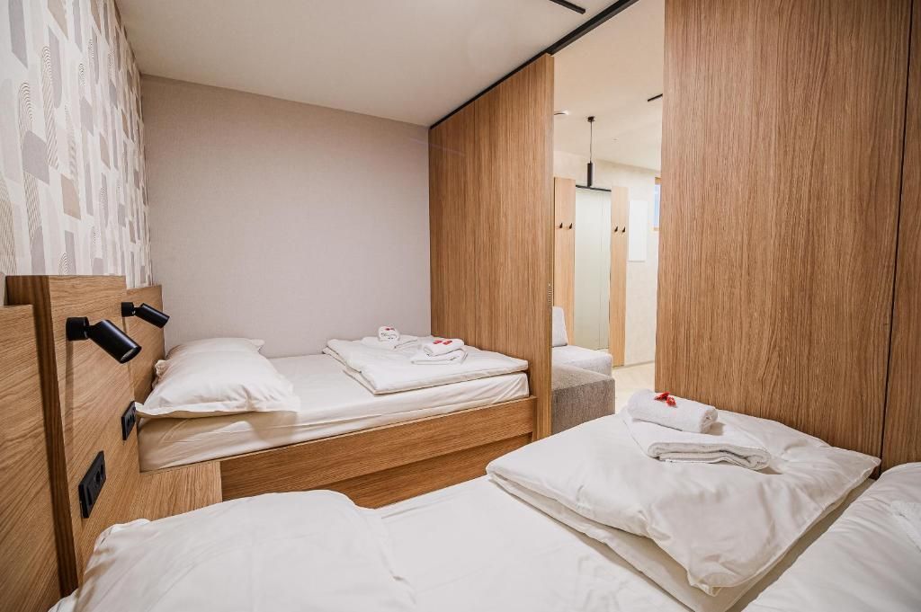 Quarto de hotel com duas camas, cabeceiras de madeira e um espelho grande.