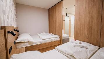 Quarto de hotel com duas camas, cabeceiras de madeira e um espelho grande.