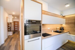 Cozinha moderna com armários brancos, forno embutido e bancada de madeira.