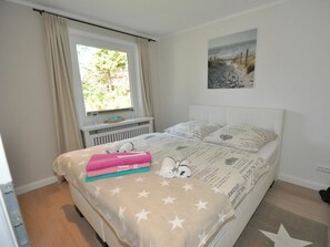 Ein Schlafzimmer mit einem Bett, einem Fenster, einer Heizung und einem Bild an der Wand.