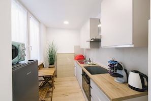 Eine kompakte Küchenzeile mit Kühlschrank, Mikrowelle, Spüle und Wasserkocher.