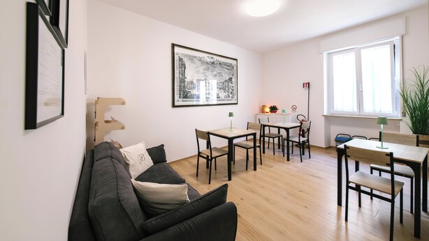 En moderne stue med sofa, spisebord med stole, et billede i ramme på væggen og et vindue med udsigt.