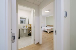 Ein Zimmer mit Holzboden, einem Bett mit floralem Überwurf, einem Nachttisch und einem Beistelltisch.