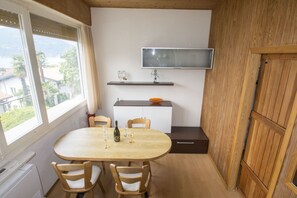 A compact kitchen with a dining table, chairs, and a TV mounted on the wall.
