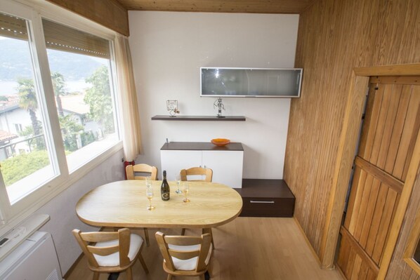 A compact kitchen with a dining table, chairs, and a TV mounted on the wall.