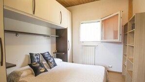 A bedroom with a bed, a wardrobe, a radiator, and a window.