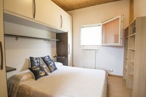 A bedroom with a bed, a wardrobe, a radiator, and a window.