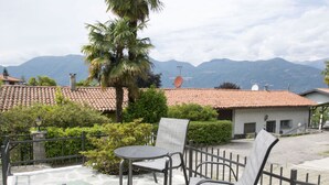 A patio with a table and chairs, a palm tree, and a view of mountains.