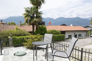 A patio with a table and chairs, a palm tree, and a view of mountains.
