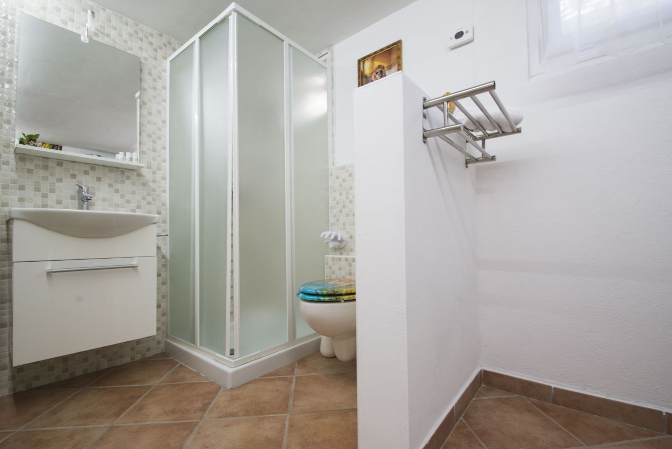Un bagno con cabina doccia, WC e lavandino.