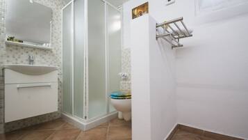 Un bagno con cabina doccia, WC e lavandino.