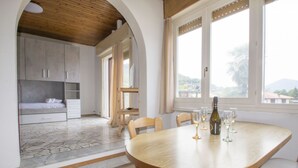 A dining area with a round table, chairs, and a bottle of wine.