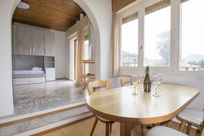 A dining area with a round table, chairs, and a bottle of wine.