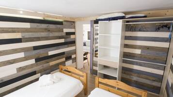 Una stanza con due letti di legno, un armadio con spazio per appendere e un rivestimento murale a listelli.