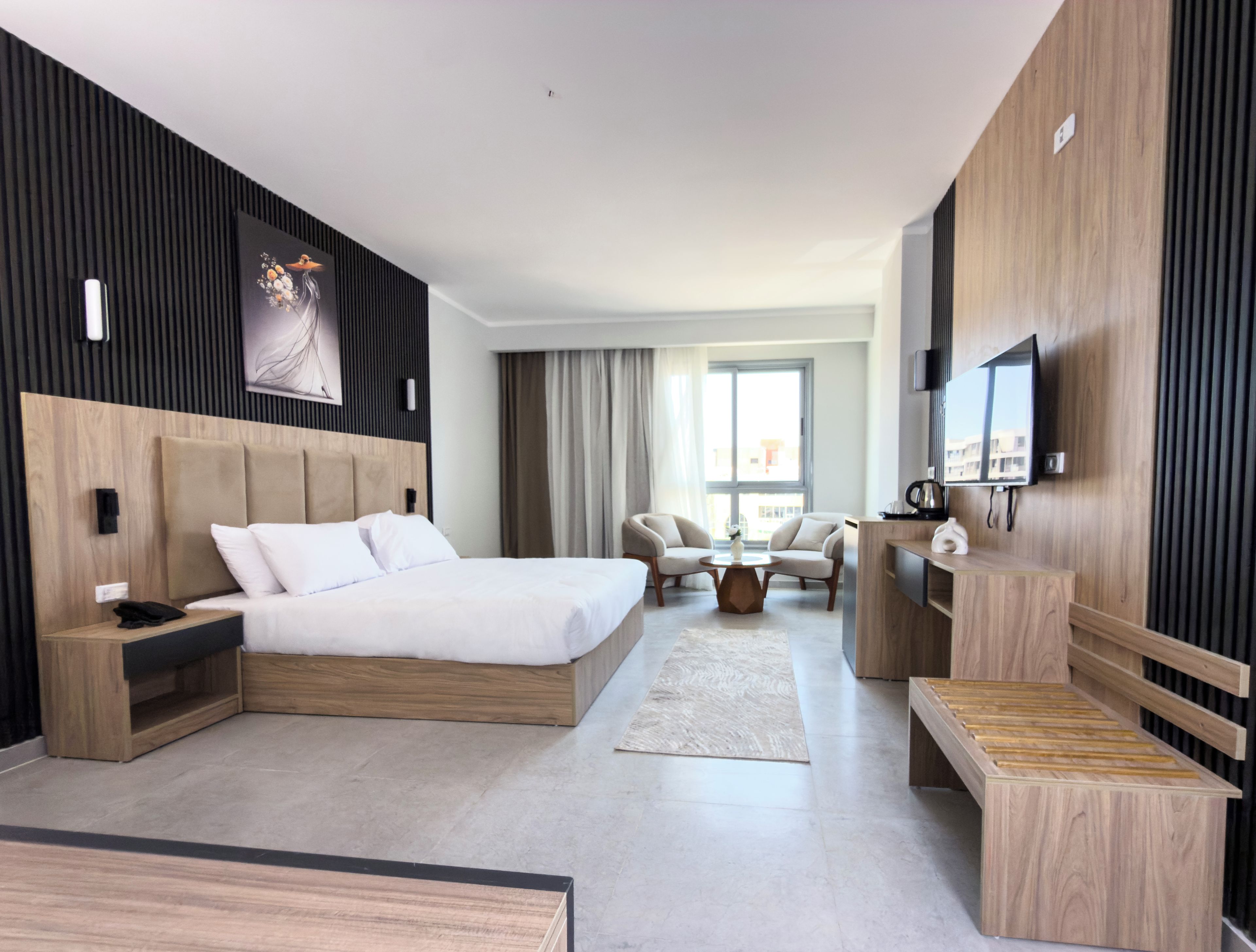 Ein modernes Hotelzimmer mit einem großen Bett, einem Schreibtisch, einem Fernseher und einer Sitzecke.