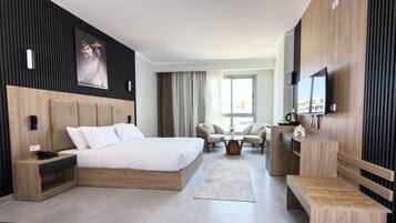Une chambre d’hôtel moderne équipée d’un grand lit, d’un bureau, d’une télévision et d’un coin salon.