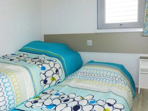 A bedroom with a bed, a window with blinds, and a bedside table. - Mediterranean Stay in France (Hyères)