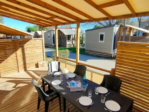 A covered outdoor dining area with a table set for two, surrounded by wooden railings. - Mediterranean Stay in France (Hyères)
