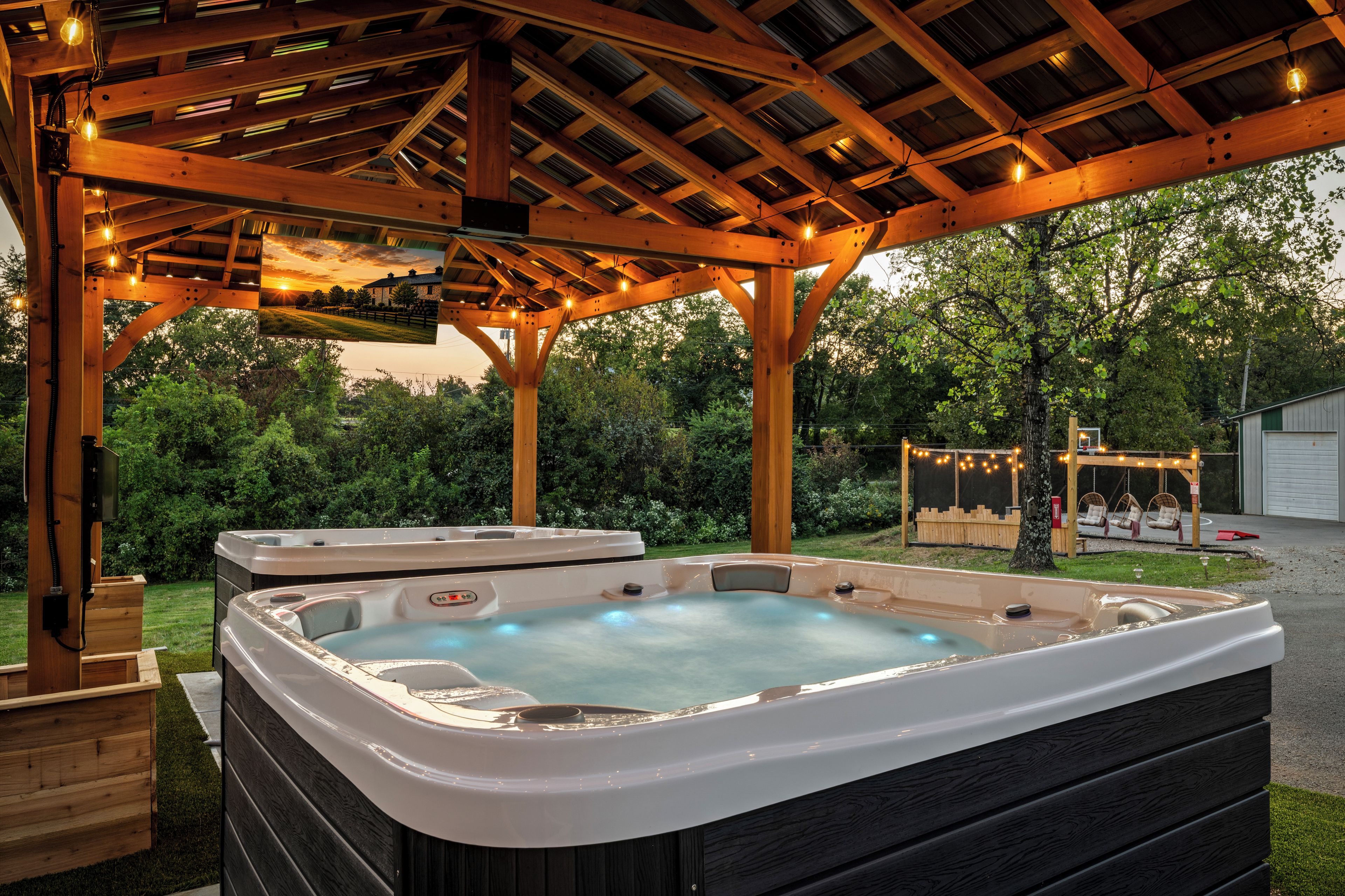 A hot tub area with a wooden pergola overhead, surrounded by greenery.