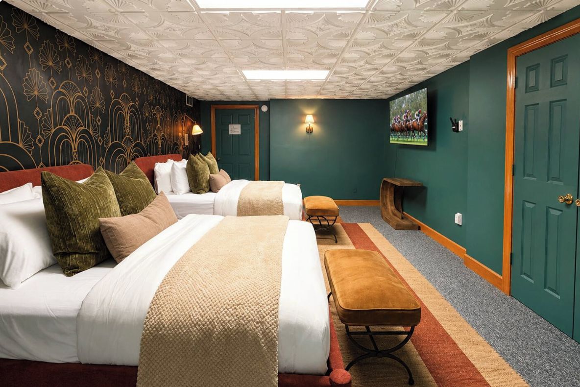 Habitación de hotel con dos camas, un banco, un televisor y una decoración de pared.