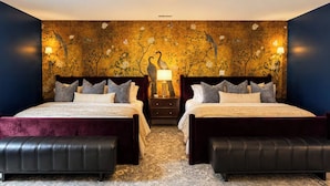 A double bed with a headboard, two bedside tables with lamps, a decorative wall with floral patterns, and a chandelier. - Golf Sim, Karaoke. SpeakEZ, 2 Hot Tubs, Sauna, Mini-Golf (Frankfort)