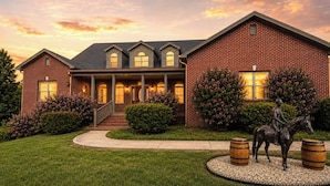 A brick house with a porch, a statue of a rider on a horse, and a landscaped garden. - Golf Sim, Karaoke. SpeakEZ, 2 Hot Tubs, Sauna, Mini-Golf (Frankfort)