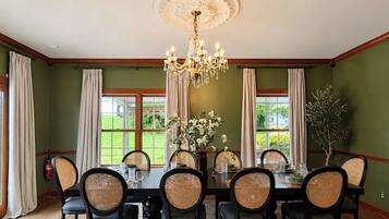 Un comedor con candelabro, paredes verdes y vistas al exterior.